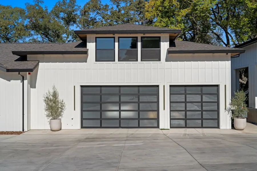 A pair of modern full-view glass garage doors on a white board-and-batten home
